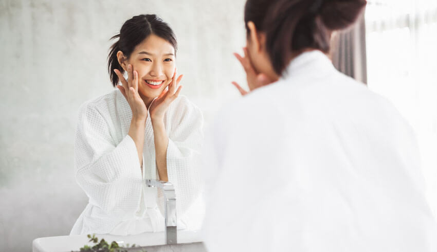 A woman applies serum to her face